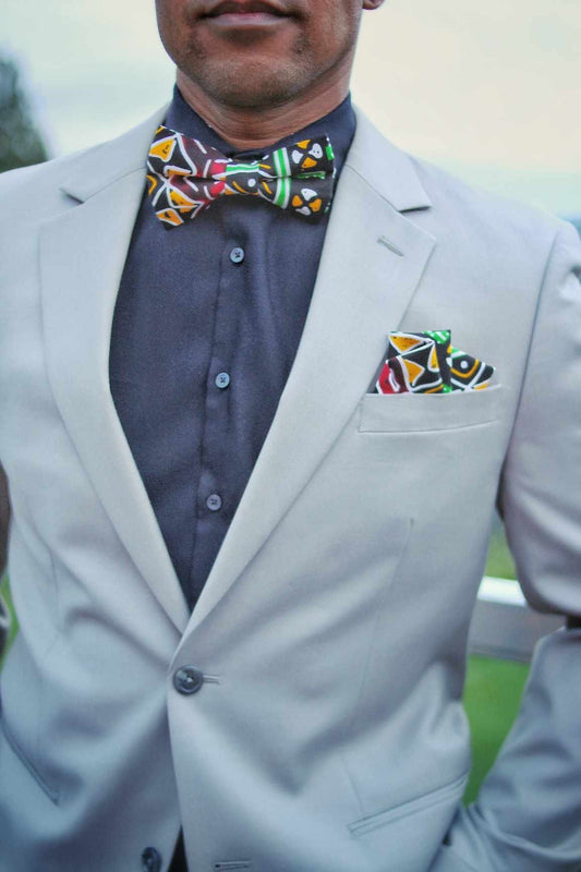 African American man wearing a multi colored black pre-tied bow tie and matching pocket square.