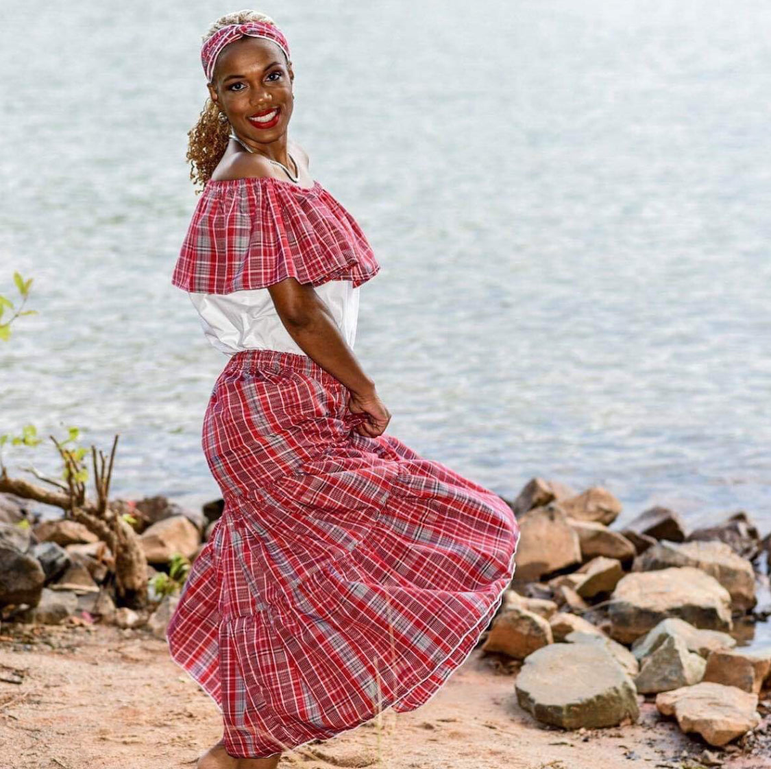 Jamaican lady wearing a traditional bandana red plaid print skirt and white and bandana print top with a headwrap