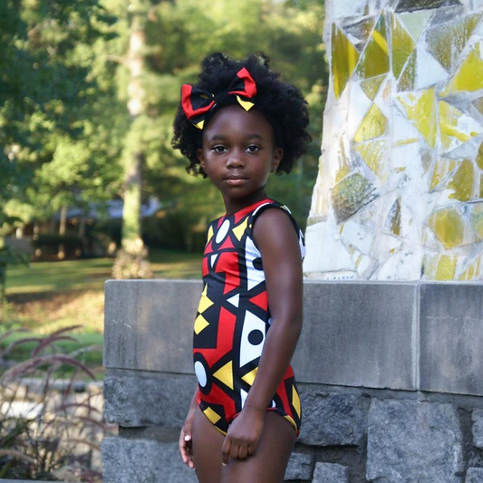 African American girl wearing a lined sleeveless African print leotard and optional hair bow with red, black, yellow and white colors for Black History and Juneteenth