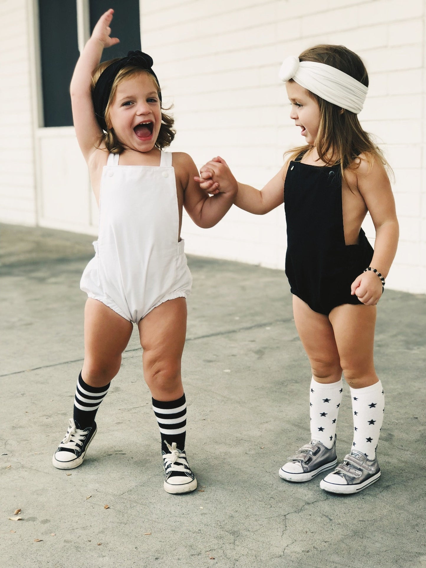 Little girls dancing in their boho sleeveless cross back style black romper and white romper