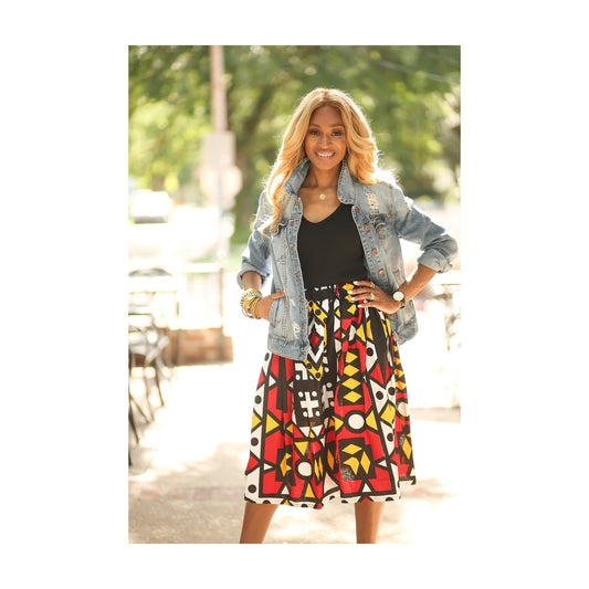 African American woman wearing an African print, red, black, yellow and white geometric print skirt.