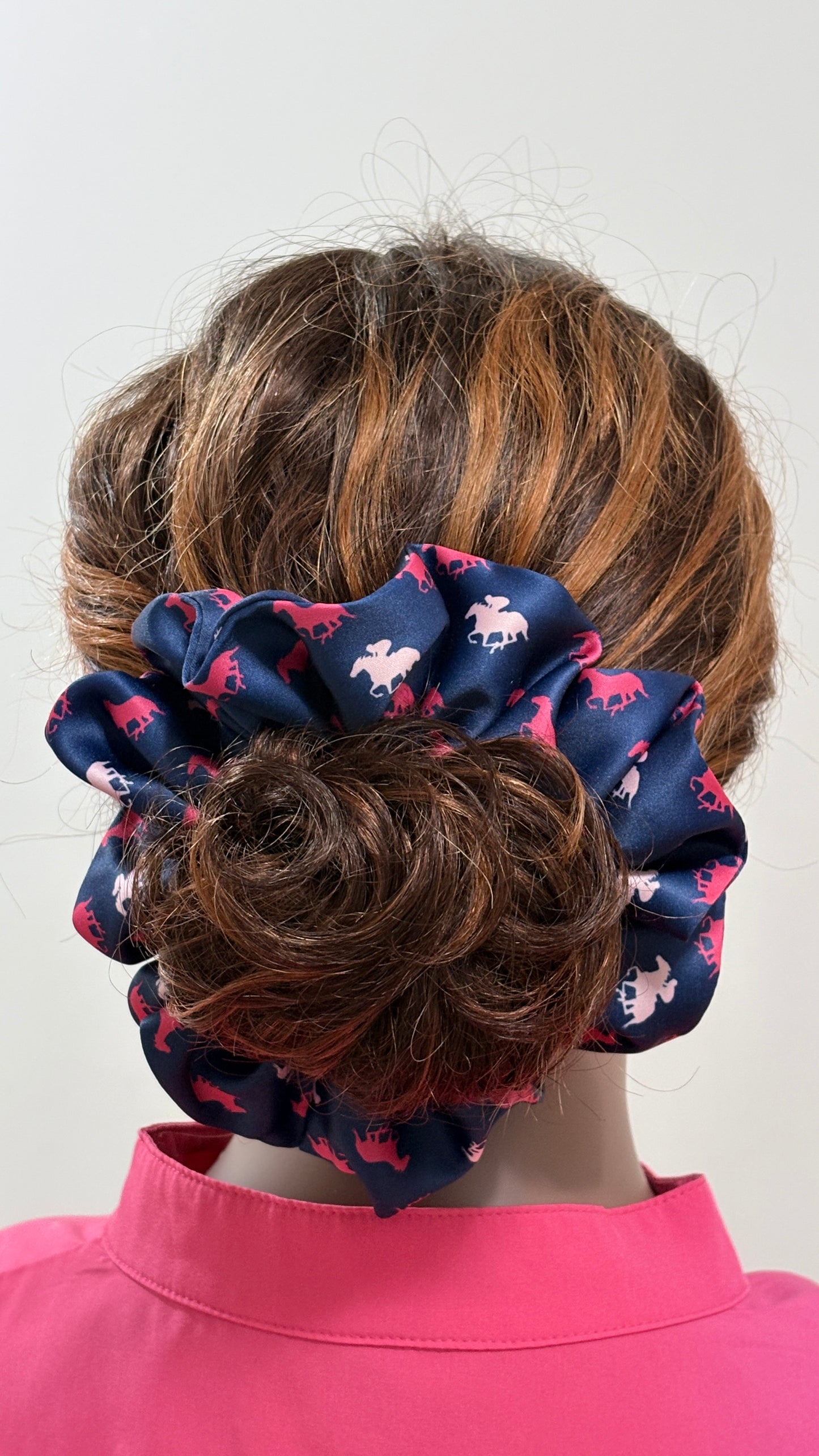 Mannequin wearing a navy blue scrunchie with pink horses galloping patterns on a white background