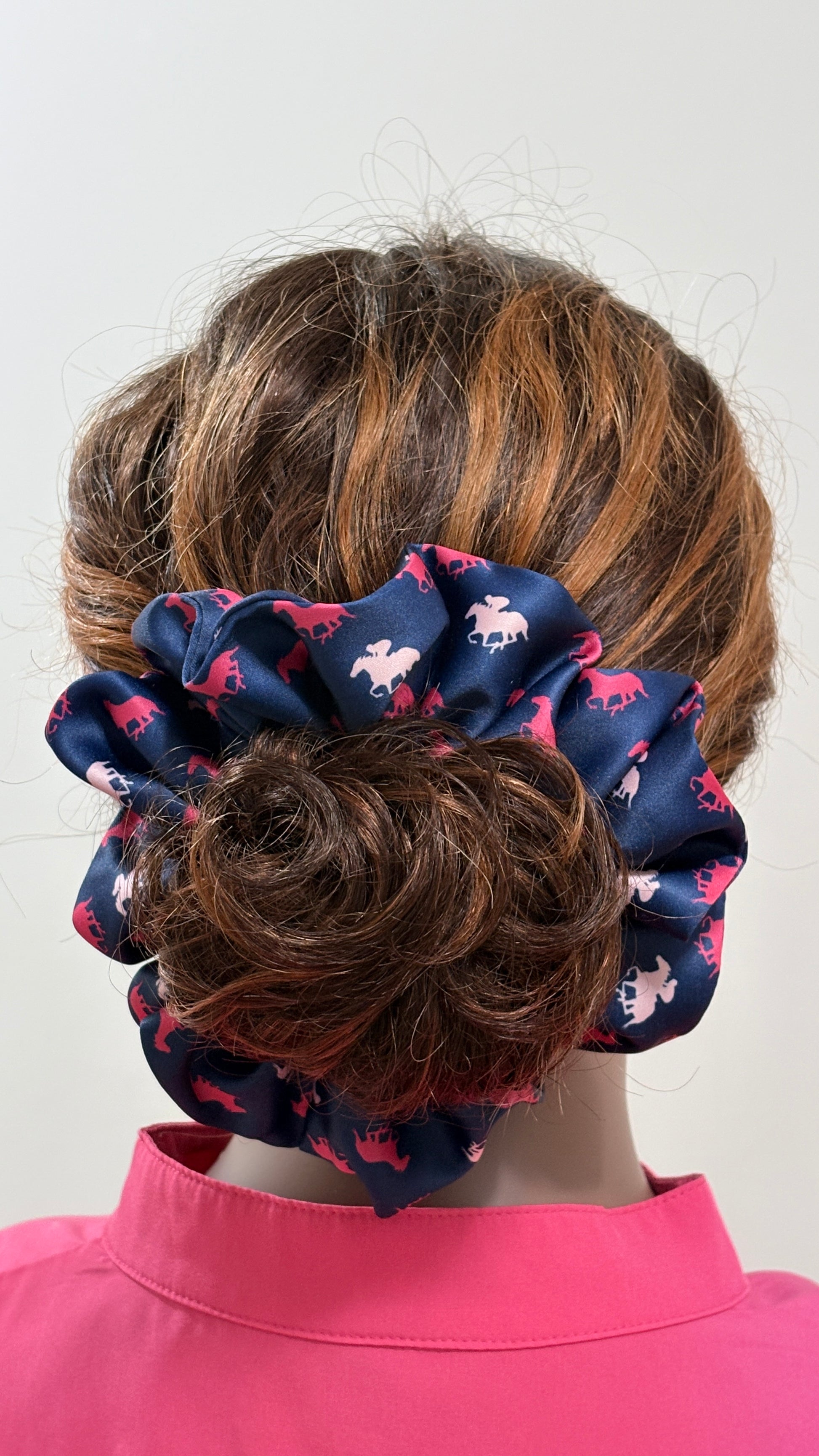 Mannequin wearing a navy blue scrunchie with pink horses galloping patterns on a white background