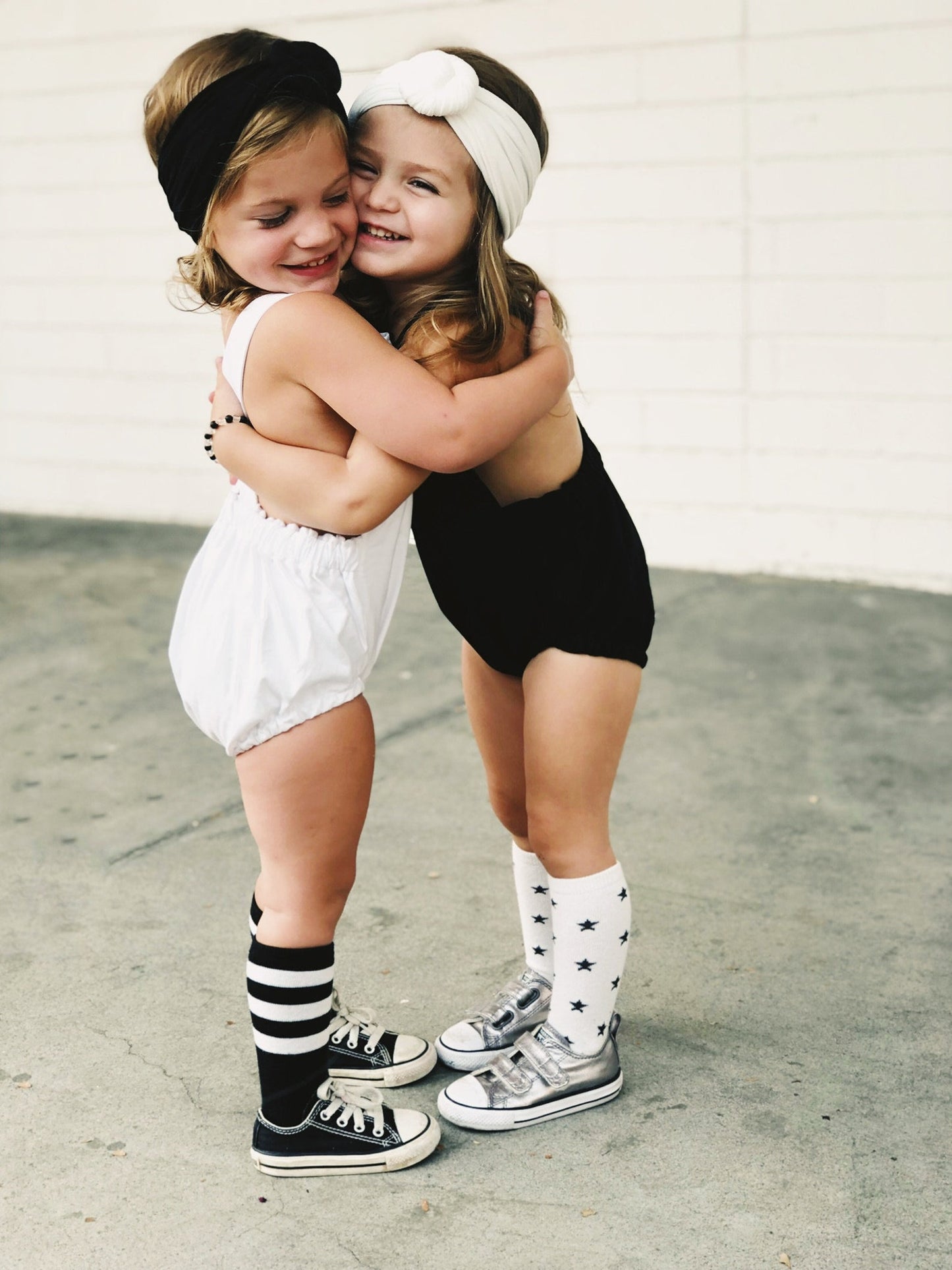 Little girls dancing in their boho sleeveless cross back style black romper and white romper