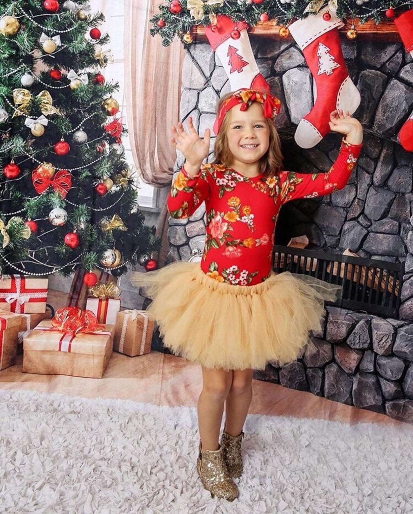 Little girl wearing our red floral long sleeve leotard and a gold tutu, with a christmas background setting. 