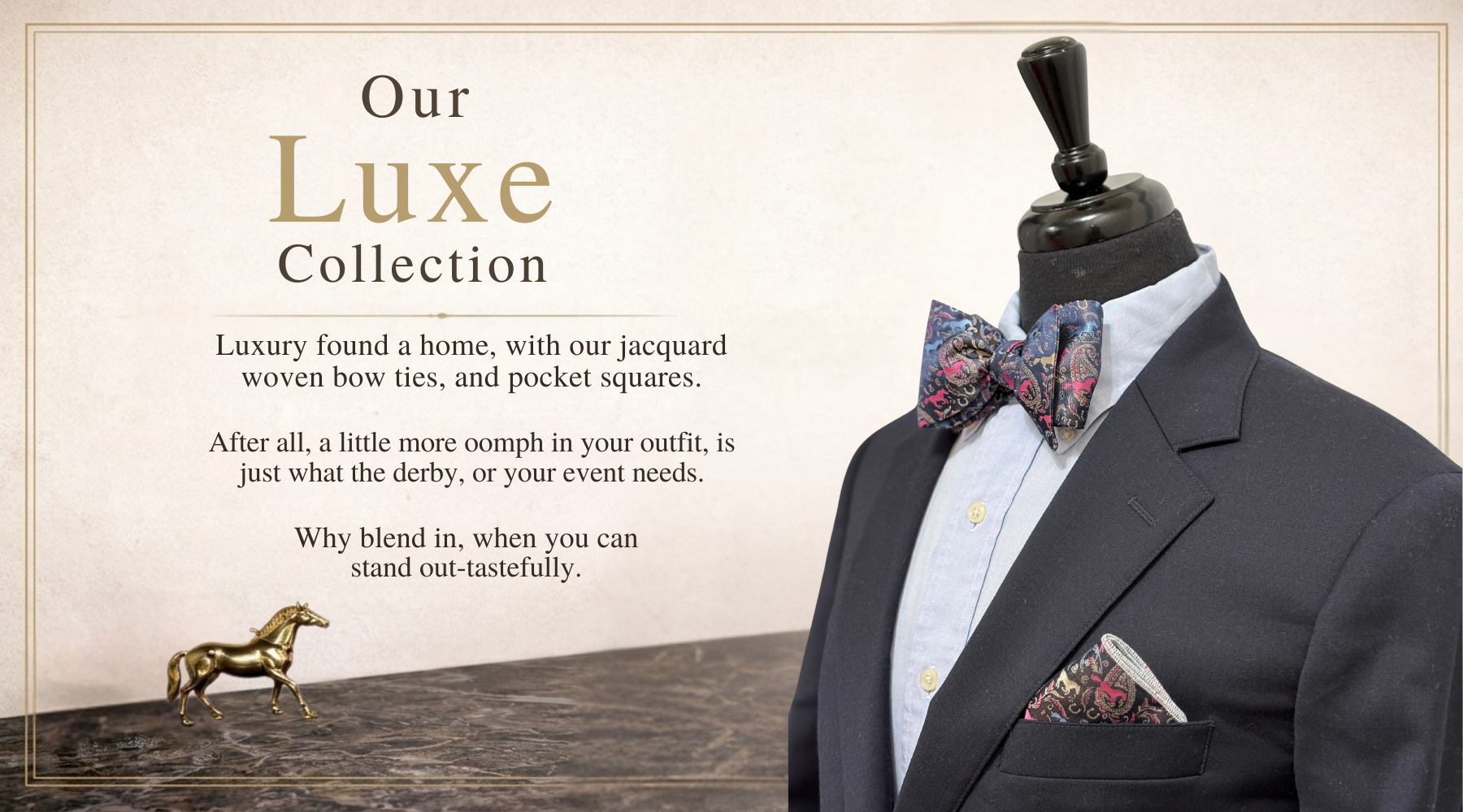 Mannequin wearing a charcoal suit with a navy with fuchsia and blue jacquard paisley horse themed bow tie and pocket square, with words on the background labeled 'Luxe Collection'.