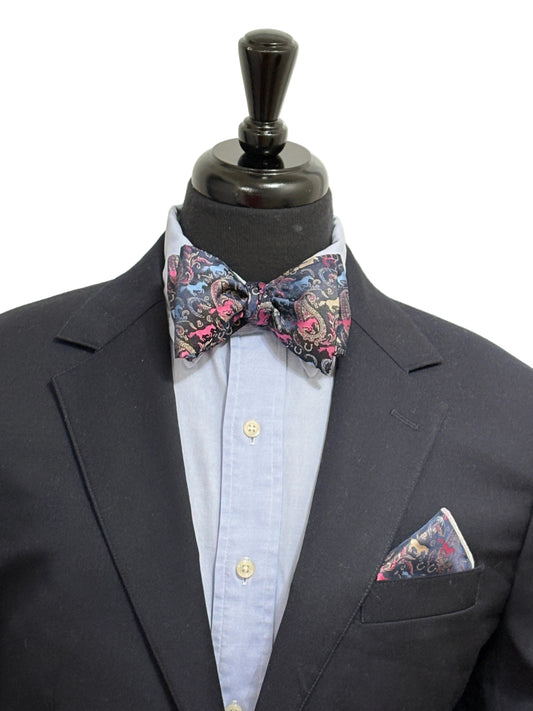 Black suit with a paisley horse theme patterned self tied bow tie and pocket square on a mannequin against a white background