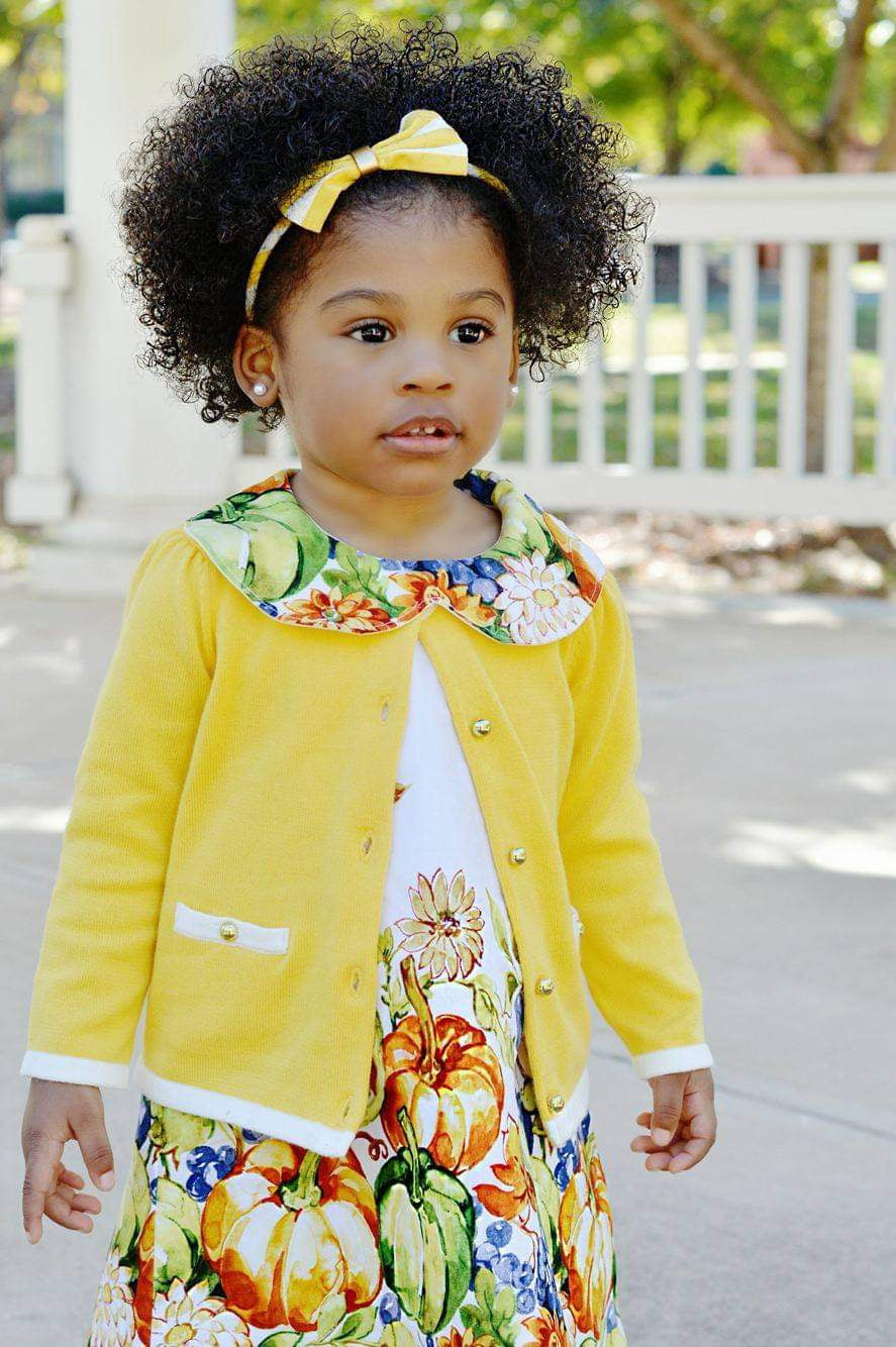 Little African American girl wearing a fall dress with collar and a harvest print with pumpkins 