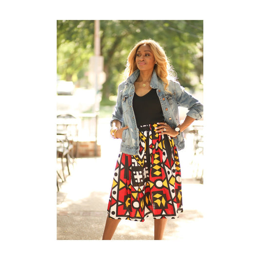 African American woman wearing an African print, red, black, yellow and white geometric print skirt. 