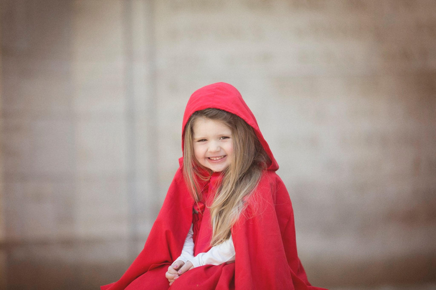 Girl wearing a Riding Hood red cape with oversized hood as Halloween costume