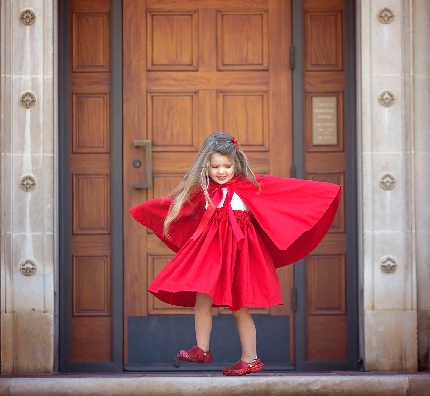 Girl twirling in Red Riding Hood cape suitable for Halloween 